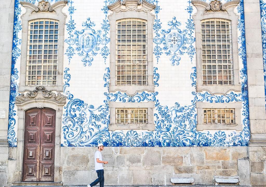 A man walks infront of azulejo facade of Carmo Church in Porto