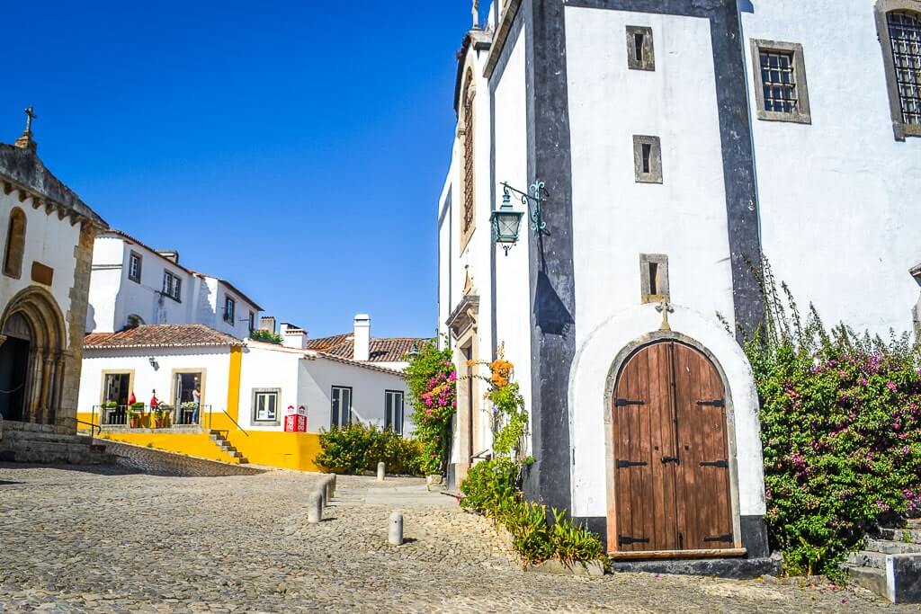 Church in Obidos with a yellow house behind