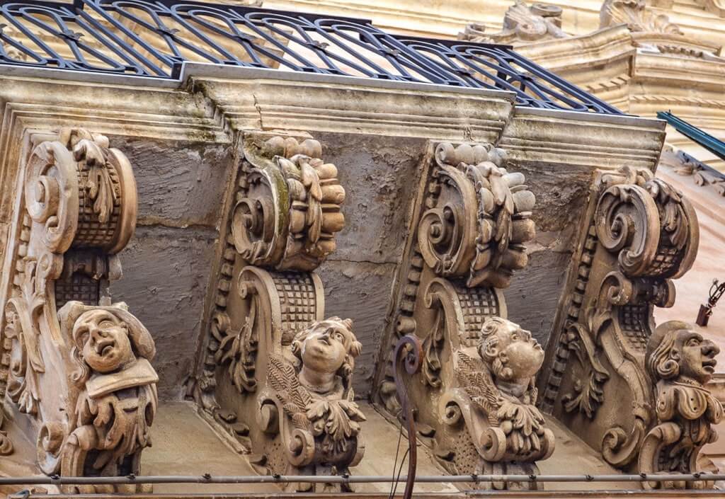 Baroque balconies with grotesque masks in Modica